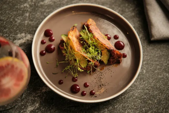 a plate of food on a table next to a glass of wine